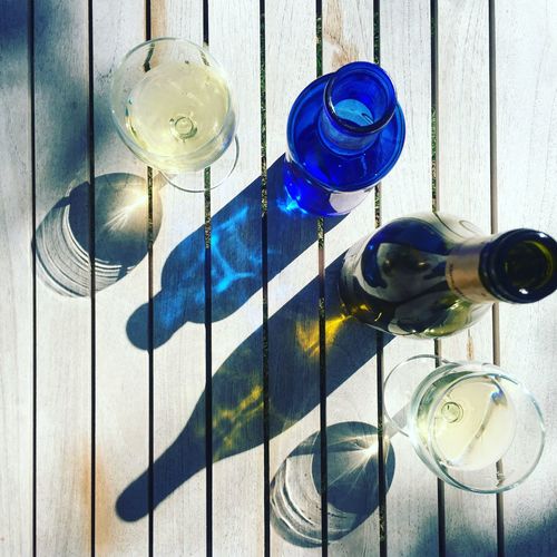 Directly above shot of wineglass and bottles on table during sunny day