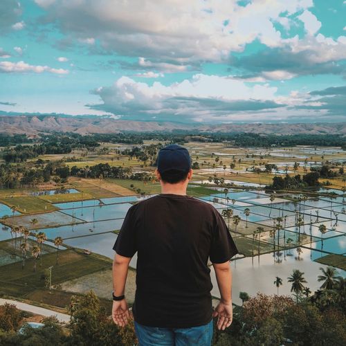 Rear view of man standing against agricultural field