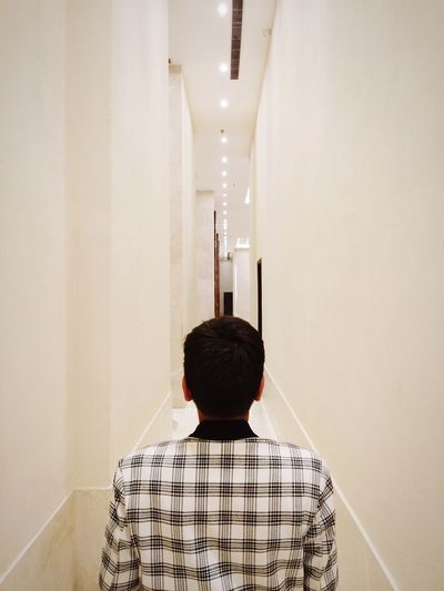 Rear view of boy standing in corridor
