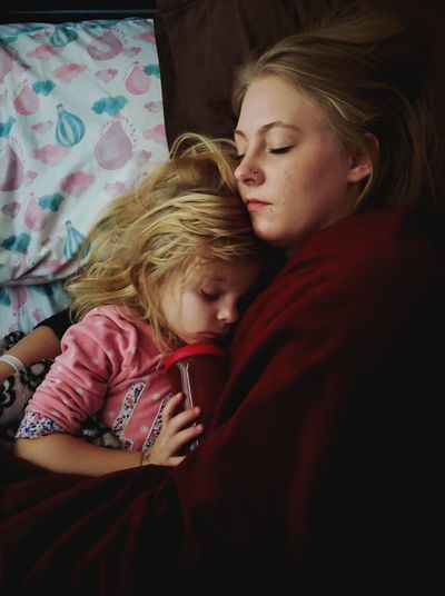 Mother and daughter sleeping on bed