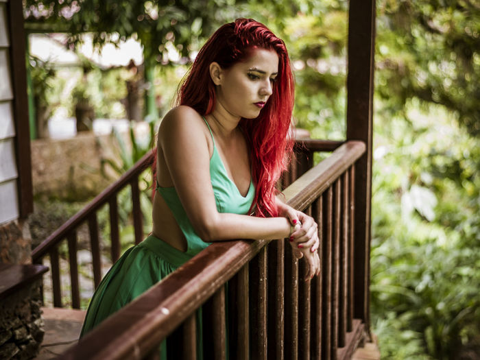 Young woman looking down while standing by railing