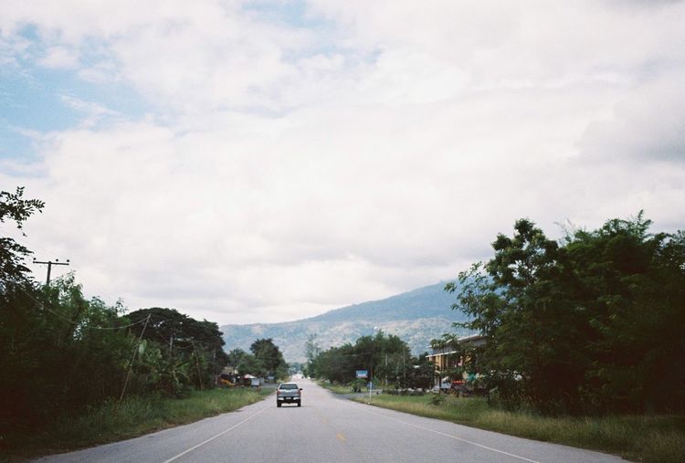 Road amidst trees against sky