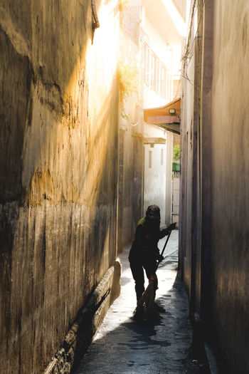 Rear view of man walking on alley amidst buildings