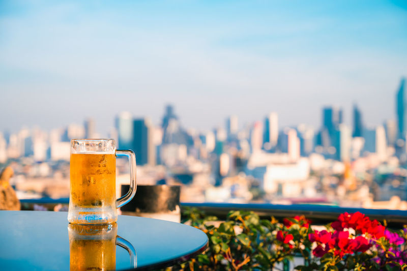 Close-up of beer glass on table against cityscape