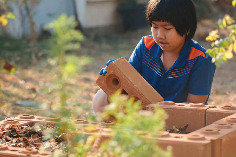 Boy arranging bricks outdoors