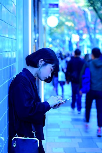 Side view of woman using mobile phone in city
