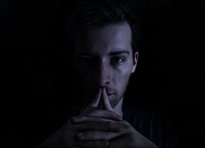 Portrait of man with hands clasped in darkroom