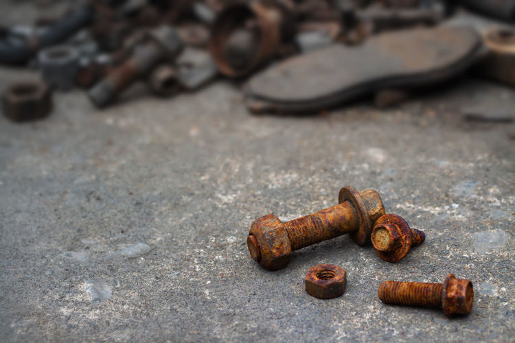 Group of old rusty nuts and screws pile on the dusty cement floor.