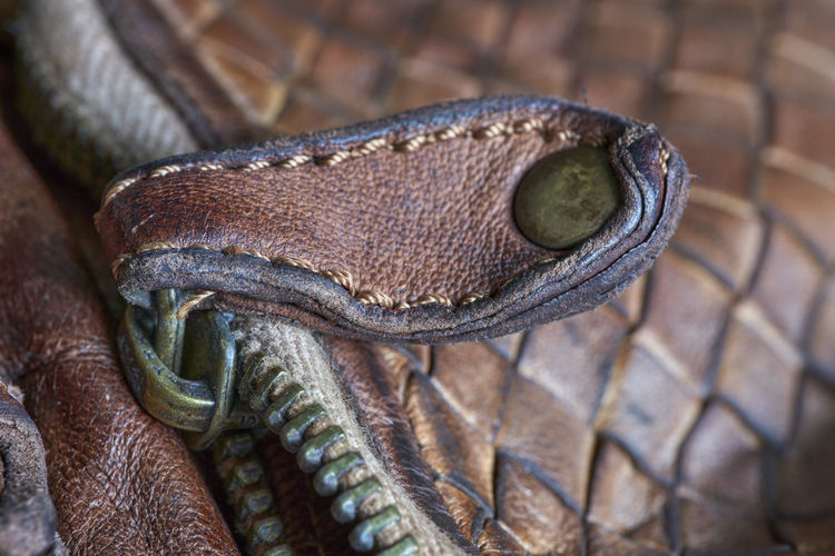 Close-up of a zipper of a brown, weathered leather handbag
