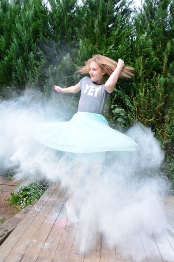 Girl dancing amidst dust on floorboard in back yard