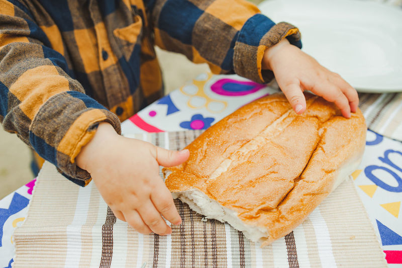 Small hand child in checkered rustic child is holding fresh homemade bread. selective focus