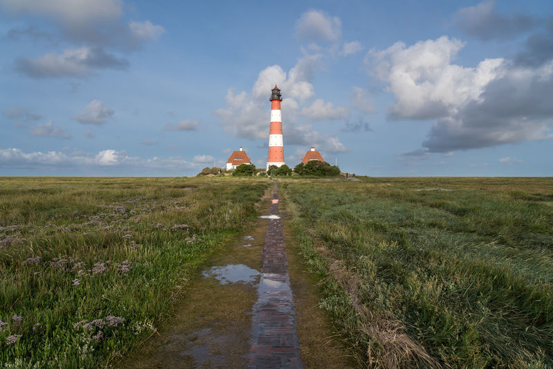 Lighthouse amidst field against sky
