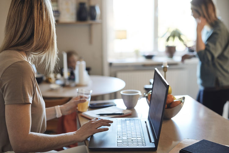 Female freelancer looking away while sitting with laptop at home