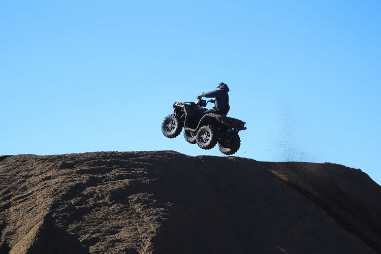 Low angle view of man riding motorcycle against clear blue sky