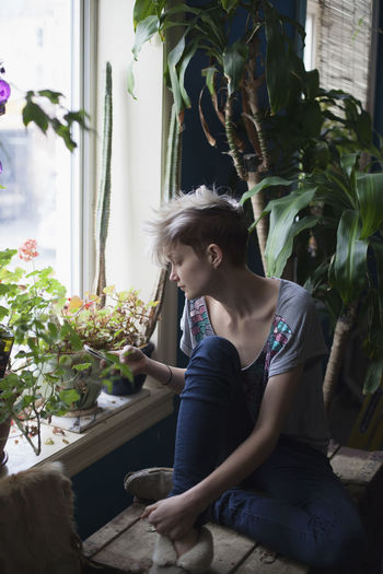 WOMAN SITTING BY POTTED PLANT