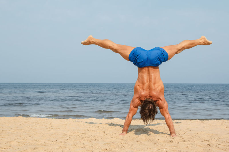 Man practicing handstand at beach