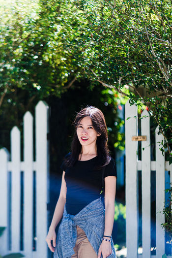 Portrait of young woman standing against plants