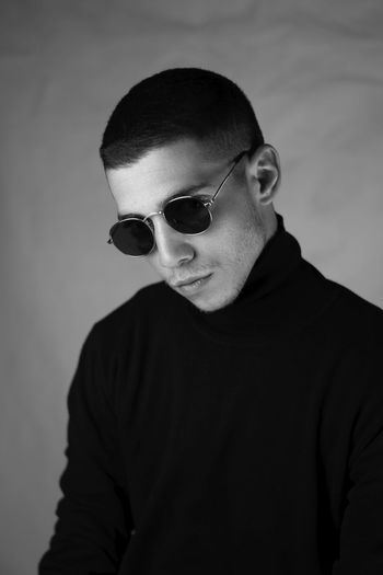 Young man wearing sunglasses against curtain 