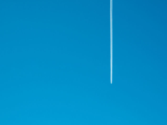 LOW ANGLE VIEW OF VAPOR TRAILS AGAINST CLEAR BLUE SKY