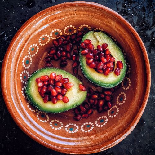 High angle view of pomegranate with avocado in bowl on slate