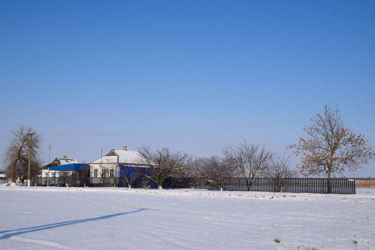 View of snow covered field against clear blue sky