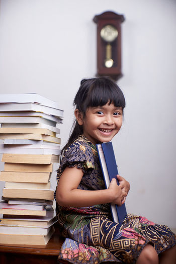 Portrait of smiling girl sitting with book at home