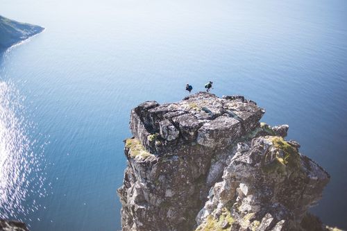High angle view of man and woman jumping on cliff