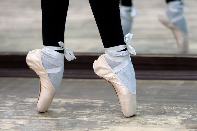 Low section of ballerina tiptoeing on hardwood floor