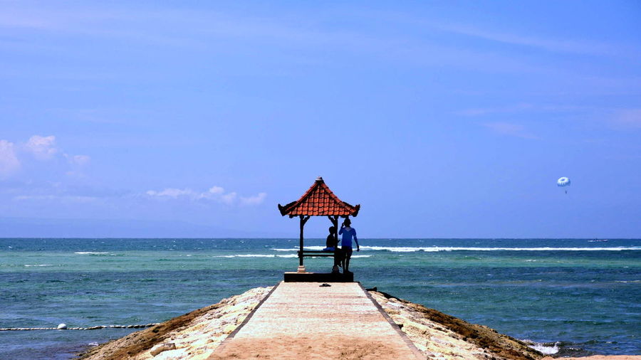 Tourists on jetty against sky