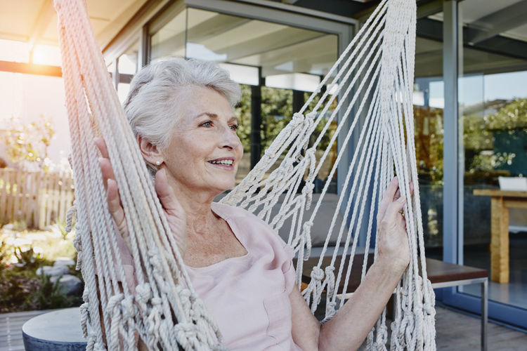 Senior woman sitting in hammock on terrace