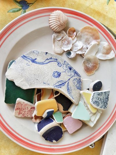 High angle view of shells and colorful ceramics in plate on table