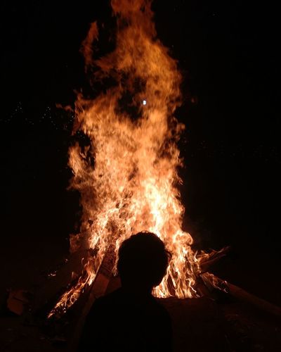 Rear view of child looking at bonfire at night