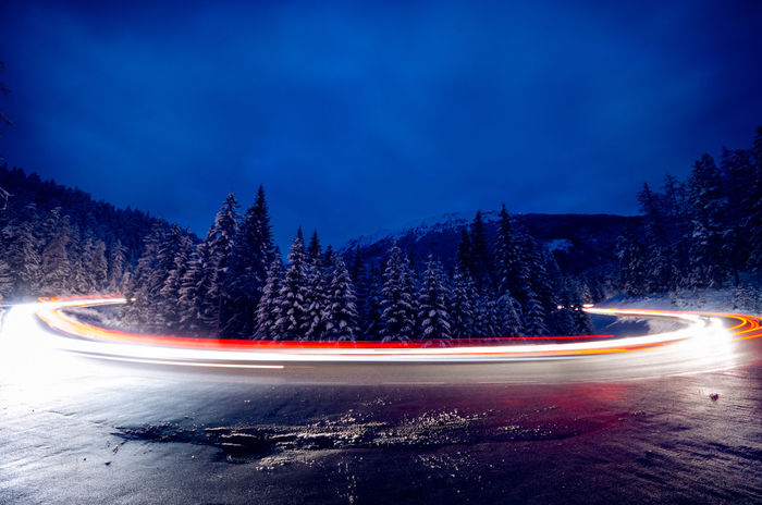 Light trails on road against sky at dusk during winter