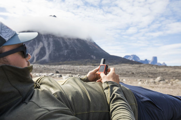 Man uses gps navigation device to plan his climbing route.