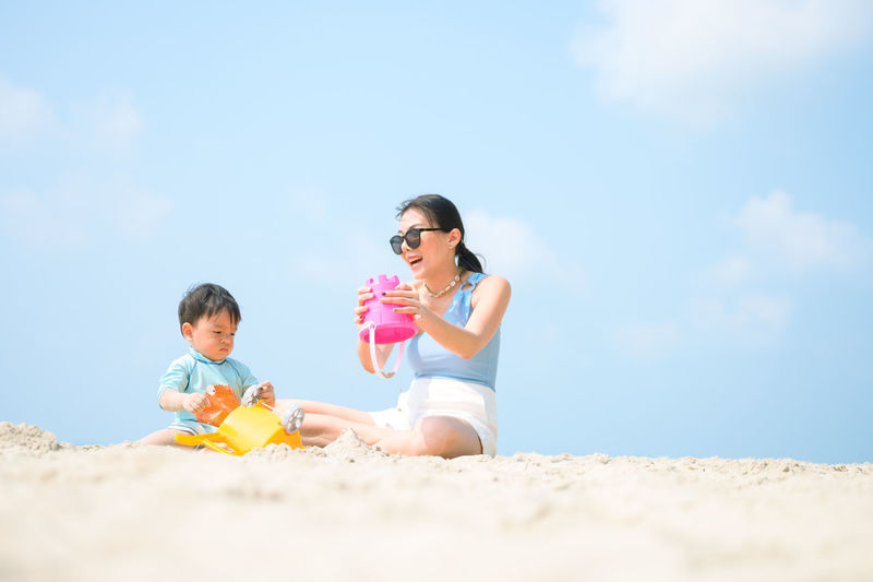 Happy friends on beach against sky