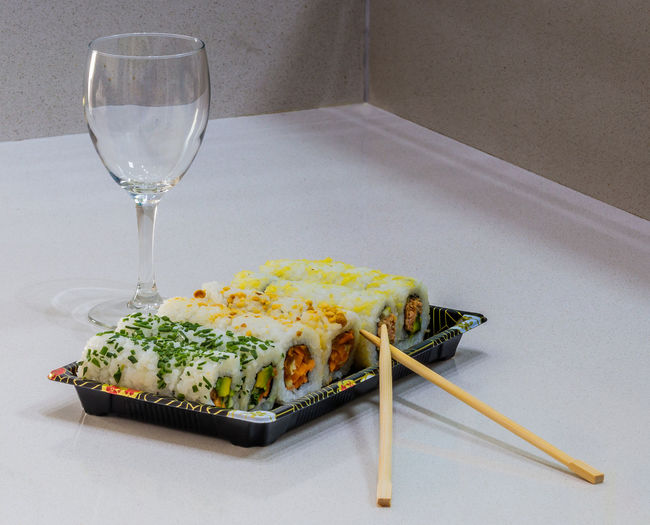 Sushi in plate by wineglass on white table