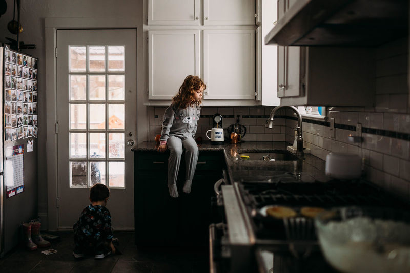 Young girl and boy wearing pjs and helping make breakfast in kitchen
