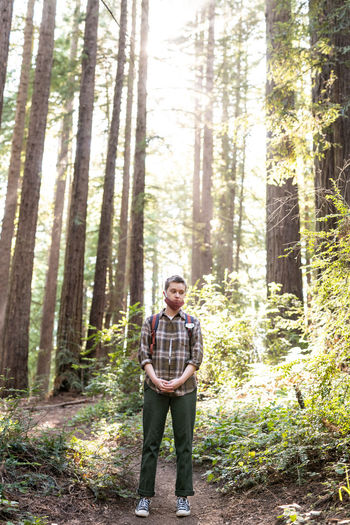 Teenage person standing in redwood grove with mask during covid-19