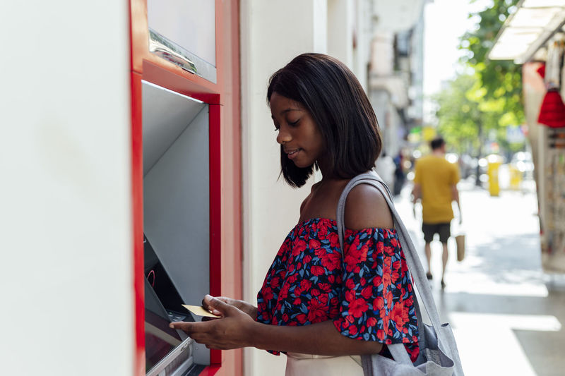 Woman with credit card standing at atm