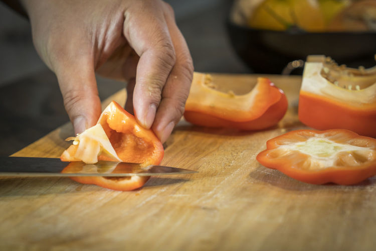Cropped hands of man chopping red bell pepper on cutting board
