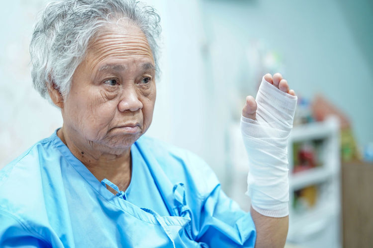Senior woman with hand wrapped in bandage looking away at hospital