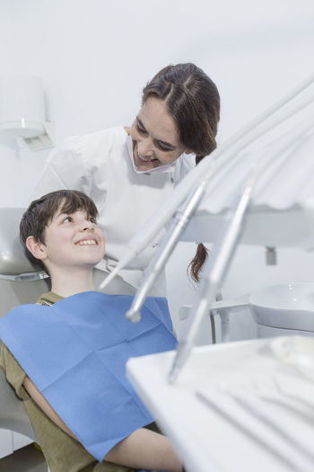 Smiling dentist examining boy tooth in clinic