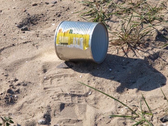 Tin can on sand at beach during sunny day