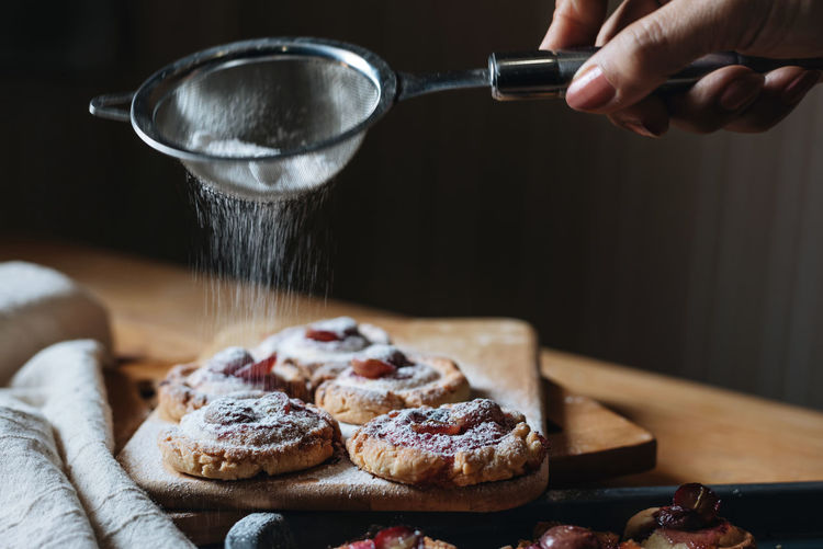 Cropped hand sprinkling powdered sugar on food