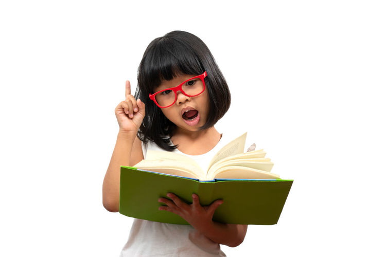 Portrait of young woman reading book against white background
