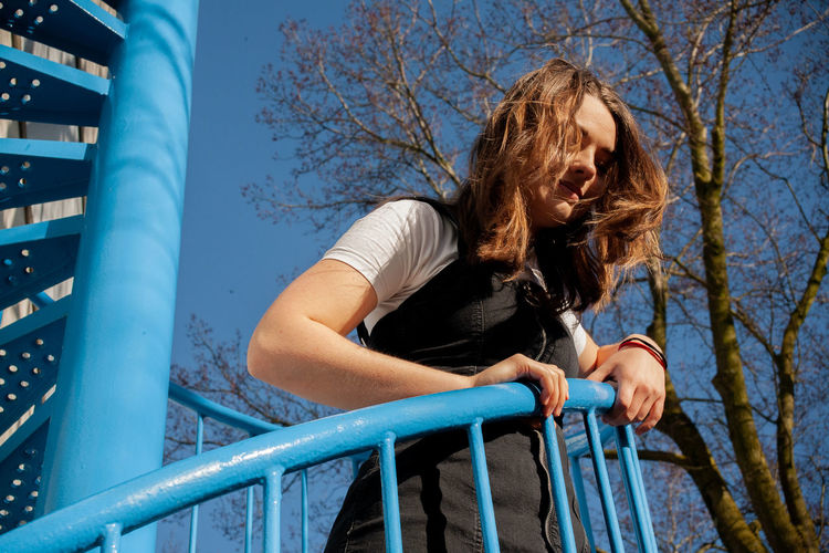 Low angle view of woman looking away while standing on railing