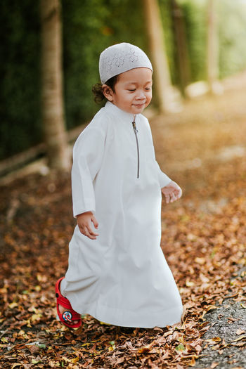 Smiling boy in traditional clothing walking on field during autumn