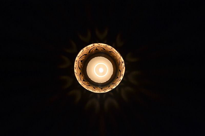 High angle view of lit tea light candle against black background