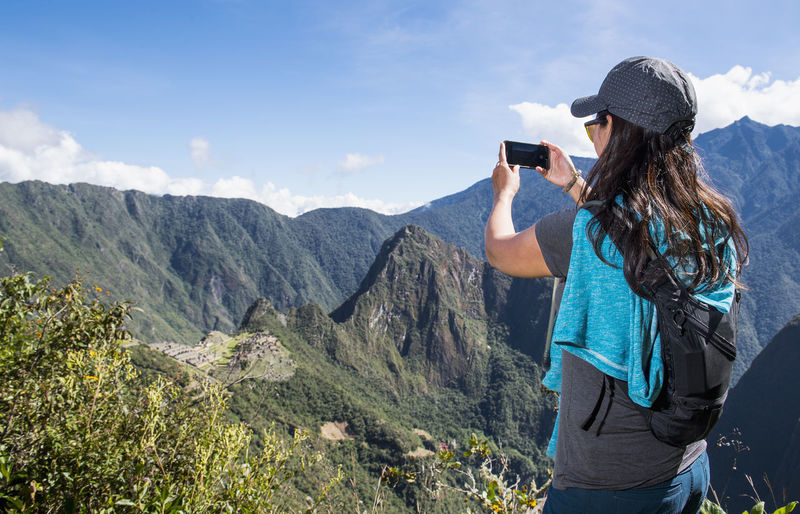 Woman takes a picture on smartphone of machu picchu on the inca trail