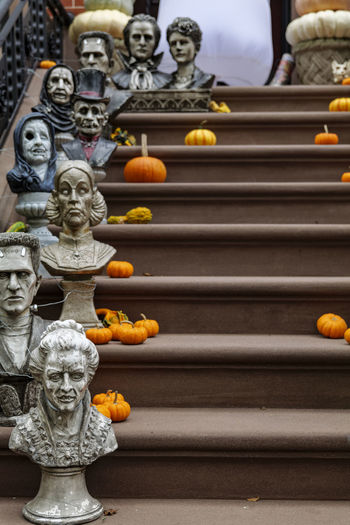 Assorted halloween decorations guard the front steps of a house. pumpkins on a porch.